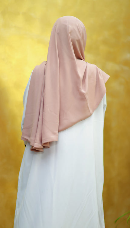 Person wearing a pink hijab and white outfit against a yellow background
